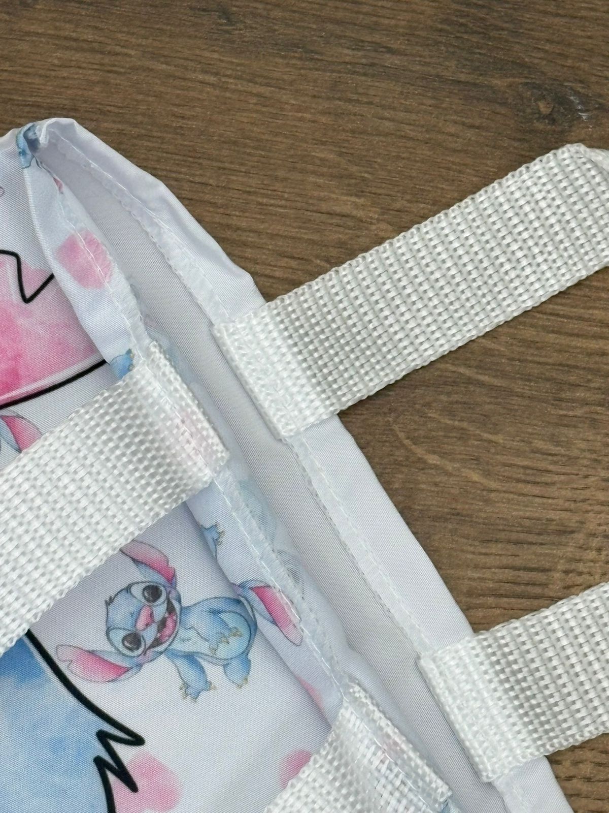 Detalhe de costura e alça branca em ecobag de referência com estampa Stitch.